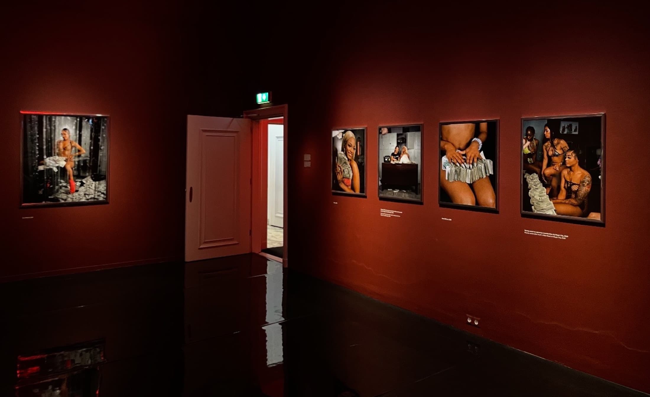 An exhibition room with deep red walls, photographs hung in a line