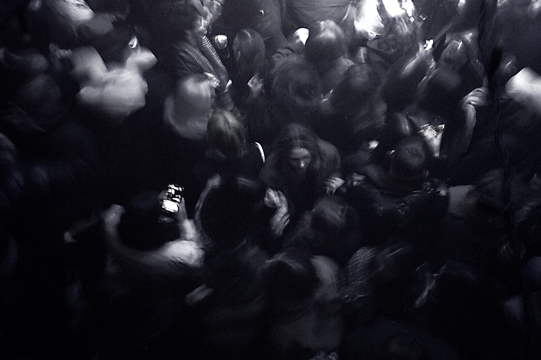 A dense crowd photographed from above in black and white, blurred with movement