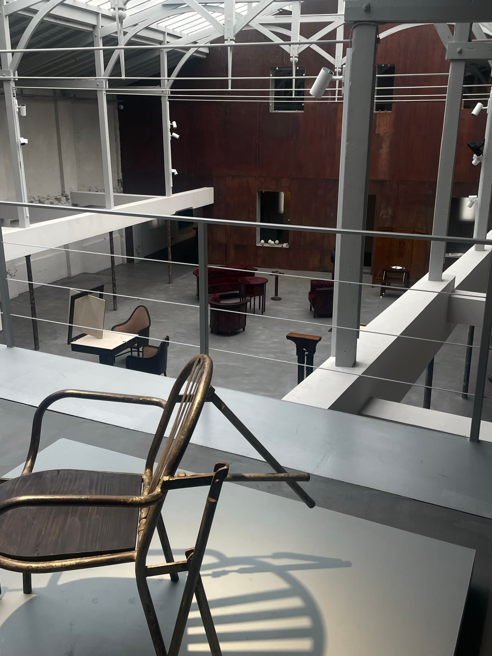 Looking down from a landing into a concrete hall with chairs and tables