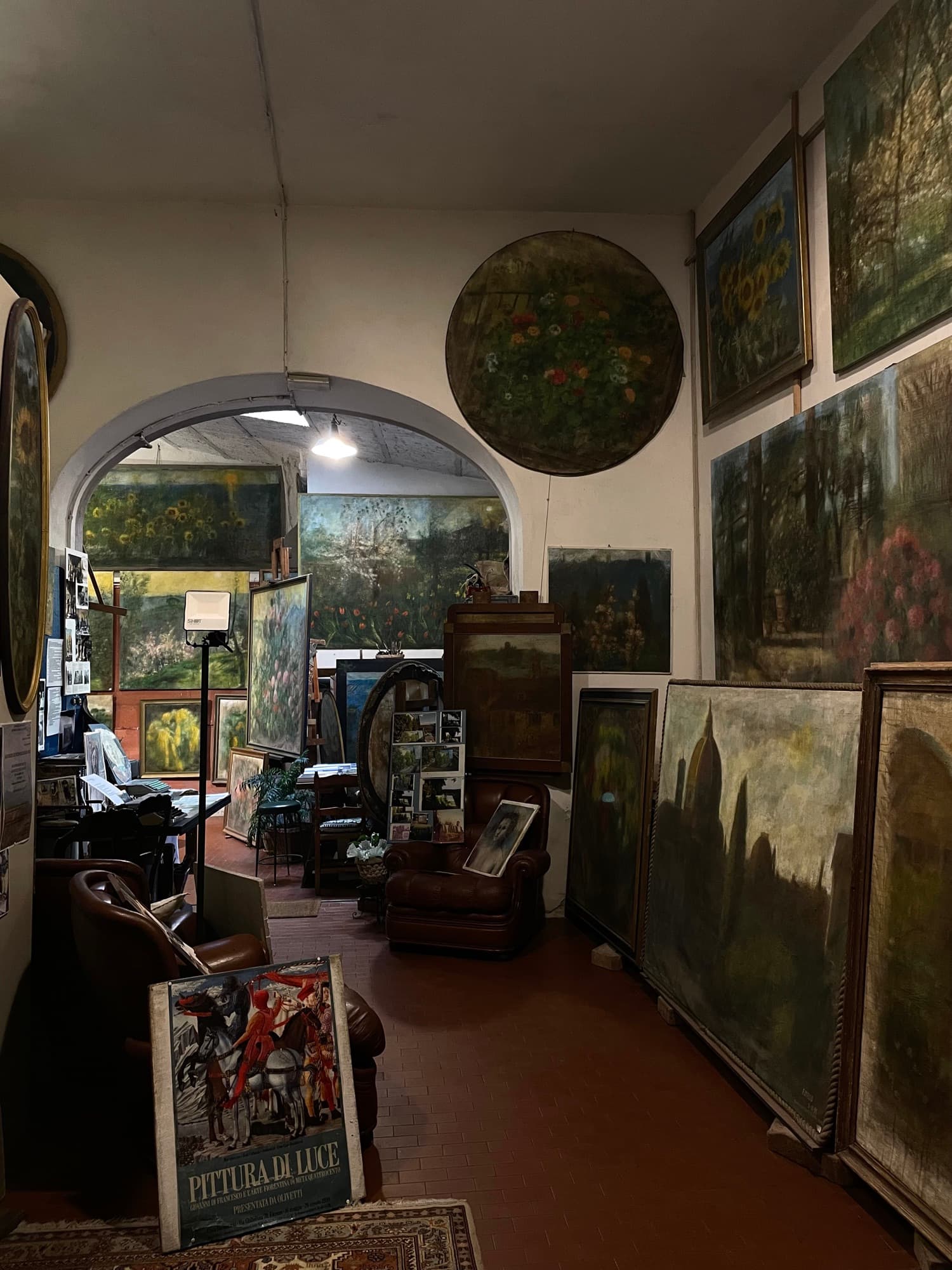 A painter's studio crowded with canvases, an arched doorway at the back