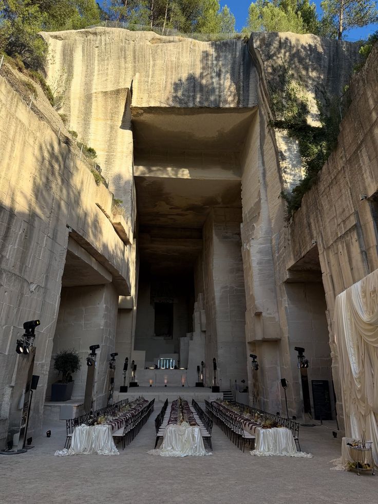 A long table set for dinner deep inside a cut limestone quarry, sheer curtains hung between the rock faces.