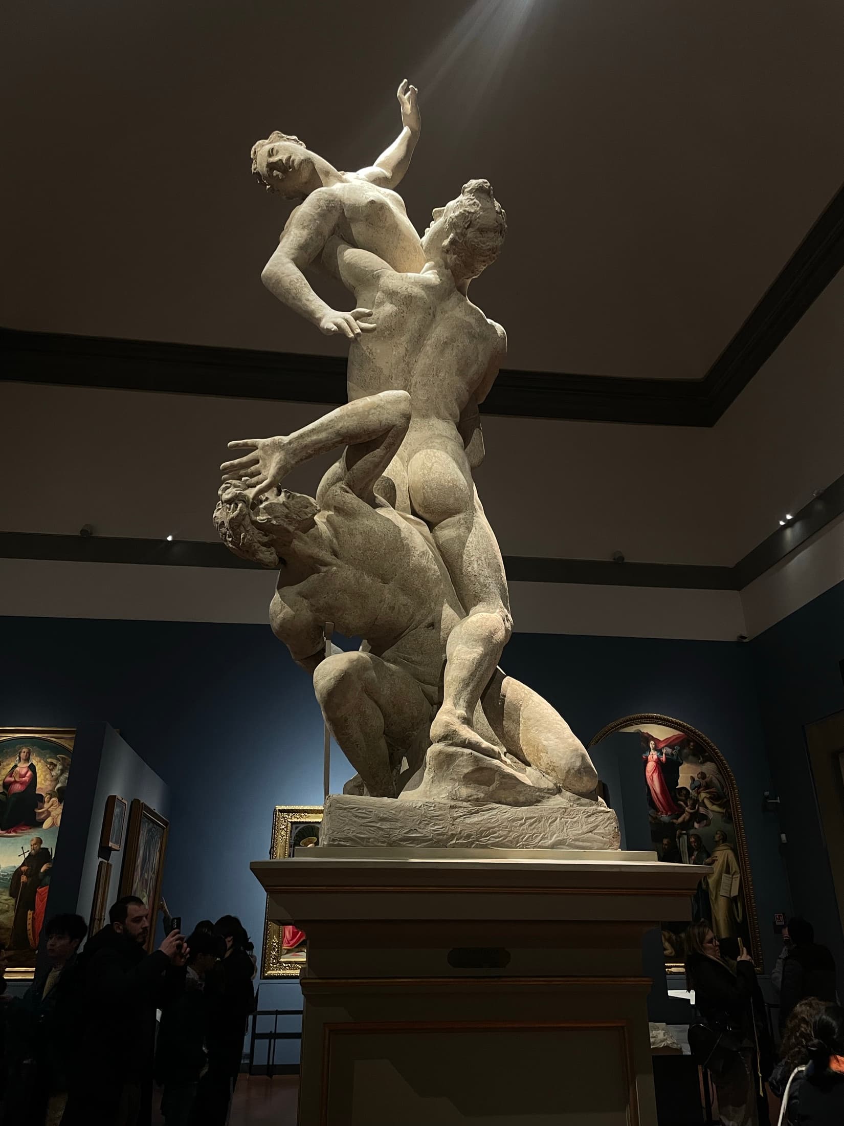 A marble sculpture group lit in a deep blue museum room